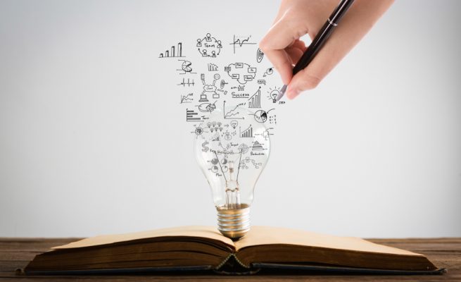 persona-dibujando-simbolos-que-salen-bombilla-encima-libro